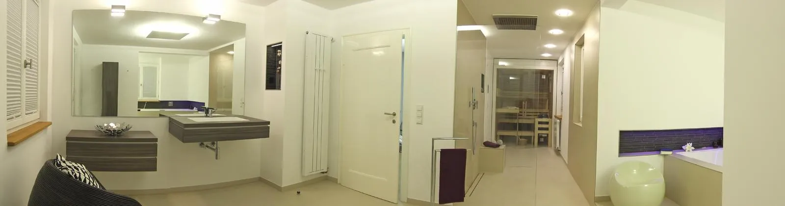 Großzügiges Wellnessbad mit modernem Waschtisch, Glasdusche, Badewanne mit LED-Beleuchtung und stilvoller Einrichtung.