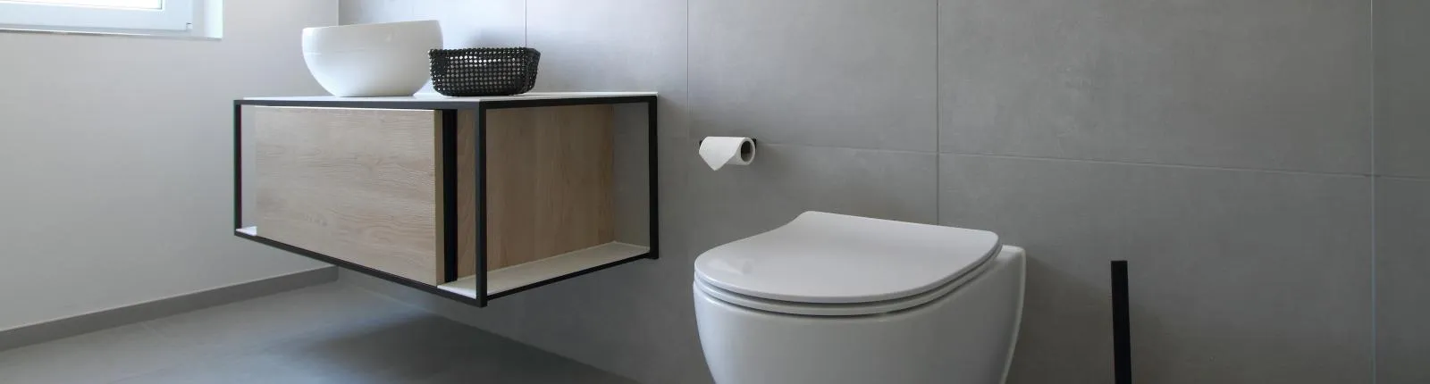 Modernes Gäste-WC in Betonoptik mit wandhängendem WC und Waschtisch in Holz-Metall-Rahmen, minimalistisch gestaltet.