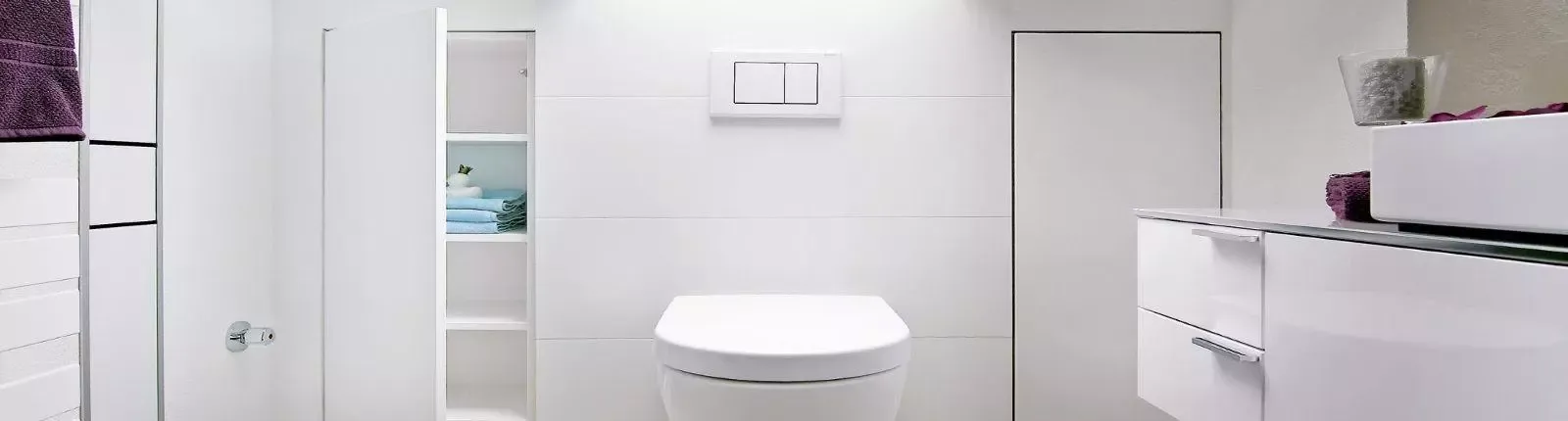 Modernes Dachbad mit wandhängendem WC, integriertem Stauraum und minimalistischem, weißem Design.