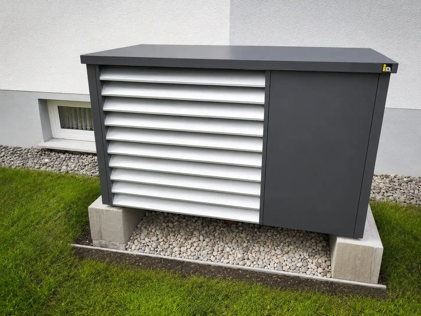 Luft-Wasser-Wärmepumpe mit modernem Schalldämmgehäuse auf einem Betonfundament neben der Hausfassade. Die Lamellenverkleidung reduziert Betriebsgeräusche und sorgt für eine unauffällige Integration in den Gartenbereich.