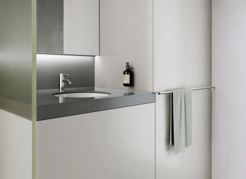 Ein minimalistischer Waschtisch mit chromglänzender Armatur und glatter grauer Oberfläche.