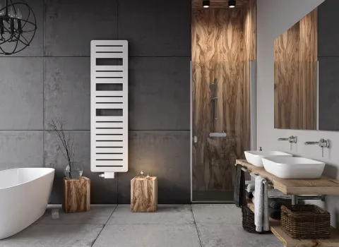 Ein modernes Badezimmer im Industrial-Stil mit Betonwänden und Holzakzenten. Eine freistehende weiße Badewanne steht links neben einem weißen, vertikal montierten Design-Heizkörper.