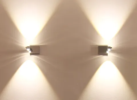 Zwei moderne Wandleuchten im Badezimmer, die durch ihr Lichtspiel eine stilvolle Atmosphäre schaffen.