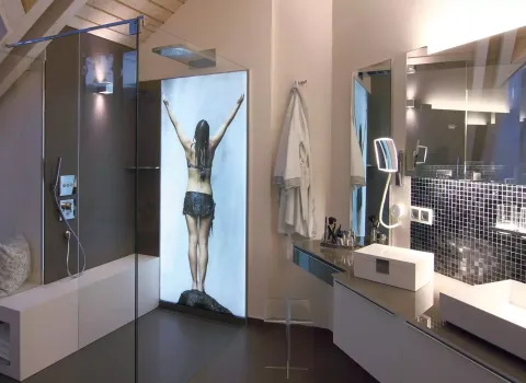 Luxuriöses Badezimmer mit moderner Glasdusche, Regendusche, beleuchtetem Wandbild und stilvollem Waschtisch mit Spiegel und Mosaikfliesen.