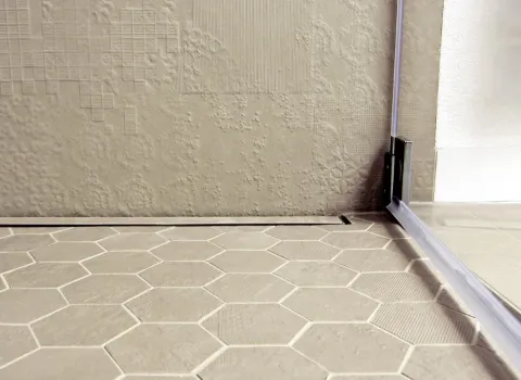 Moderne, silberne Wandarmatur mit Hebelgriff in einem eleganten Dachbad, montiert vor strukturierter Wandverkleidung.