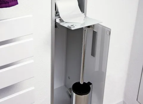Dachbad-Detail: schmaler Einbauschrank mit integriertem Toilettenpapierhalter und WC-Bürste, modern und platzsparend gestaltet.