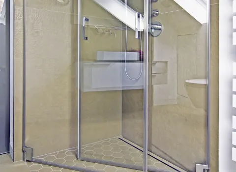 Moderne Dusche im Dachbad mit Glasabtrennung, sechseckigen Bodenfliesen und schlichter Wandgestaltung.
