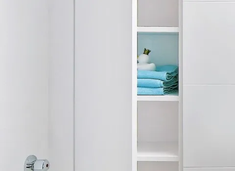 Weißer Einbauschrank im Dachbad mit geöffneter Tür, Regalfächern und ordentlich gefalteten Handtüchern.