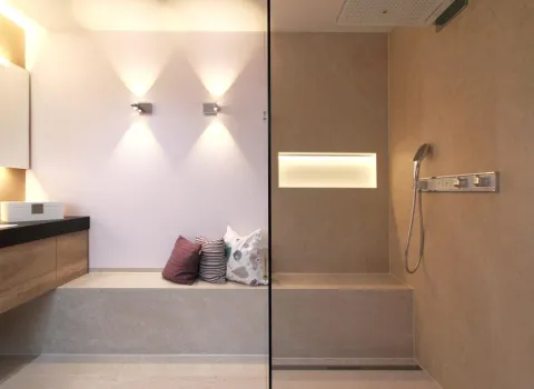 Modernes Wohnbad mit bodengleicher Dusche, integrierter Sitzbank, beleuchteter Wandnische und stilvollen Lichtakzenten.