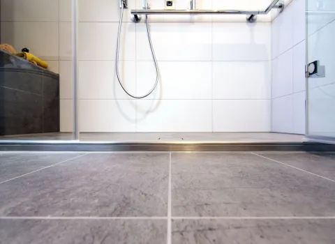 Bodengleiche, barrierefreie Dusche mit rutschfesten Fliesen und Haltegriff im modernen altersgerechten Dachbad.