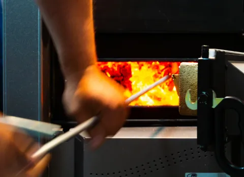 Technische Detailaufnahme eines Pelletofens mit offener Feuerkammer und brennenden Holzpellets. Die warme Beleuchtung und die sichtbare Glut unterstreichen die effiziente Wärmegewinnung der Heizungsanlage.