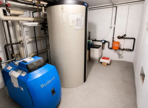 Technikraum mit energieeffizientem Buderus Heizsystem, großem Wärmespeicher und professioneller Installation. Die Kombination aus Heizkessel, Pufferspeicher und hydraulischen Komponenten ermöglicht eine nachhaltige und komfortable Wärmeversorgung.