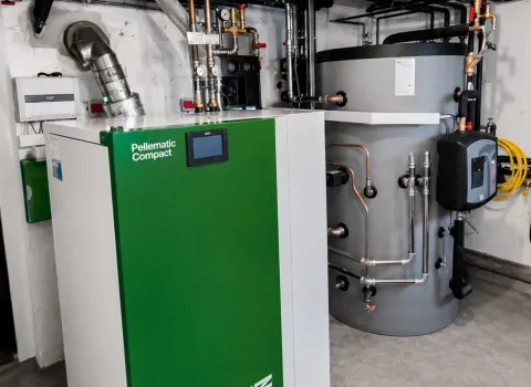 Moderne Pelletheizung mit großem Pufferspeicher in einem professionell installierten Heizungsraum. Die kompakte Biomasseheizung sorgt für eine nachhaltige und energieeffiziente Wärmeversorgung eines Wohngebäudes.