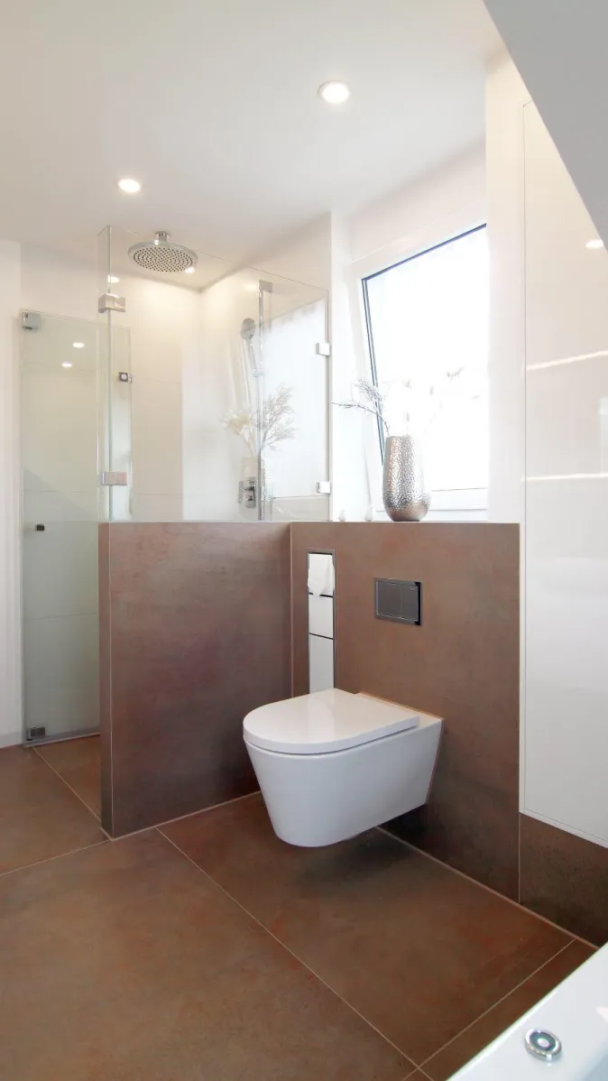 Modernes Badezimmer mit bodengleicher Glasdusche, Wand-WC und großem Fenster, gestaltet in warmen Naturtönen.