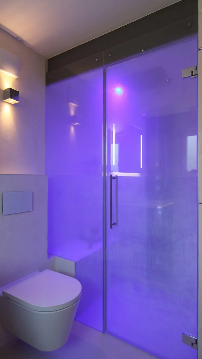 Dampfdusche mit Glasabtrennung und stimmungsvoller LED-Beleuchtung in Blau, modernes Badezimmer mit wandhängendem WC.