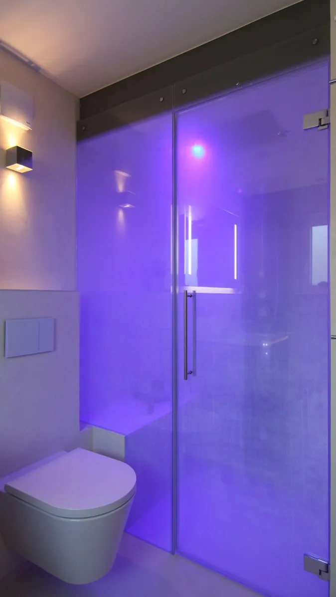 Dampfdusche mit Glasabtrennung und stimmungsvoller LED-Beleuchtung in Blau, modernes Badezimmer mit wandhängendem WC.
