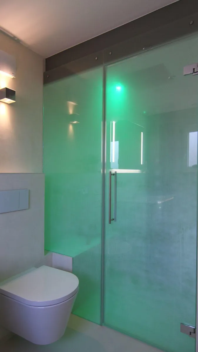 Dampfdusche mit Glasabtrennung und stimmungsvoller LED-Beleuchtung in Grün, modernes Badezimmer mit wandhängendem WC.