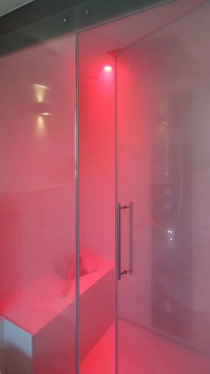 Dampfdusche mit Glasabtrennung und stimmungsvoller LED-Beleuchtung in Rot, modernes Wellness-Design.