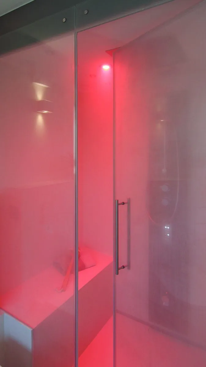 Dampfdusche mit Glasabtrennung und stimmungsvoller LED-Beleuchtung in Rot, modernes Wellness-Design.