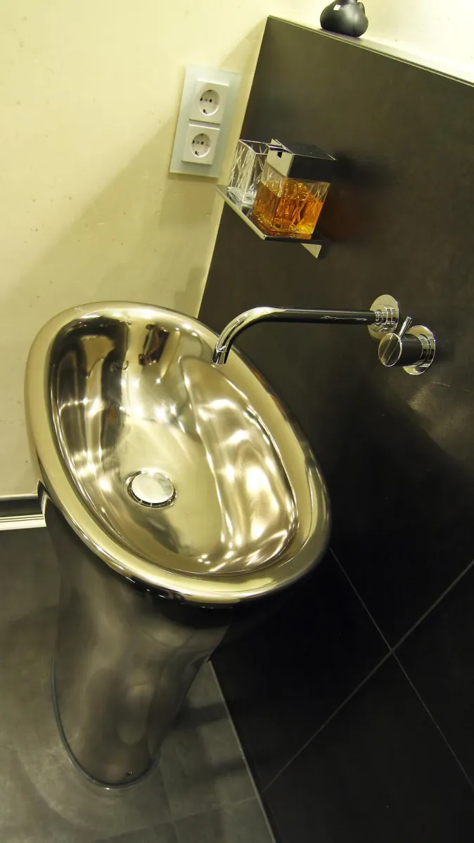 Eleganter freistehender Edelstahl-Waschtisch mit wandmontierter Armatur in einem modernen Gästebad.