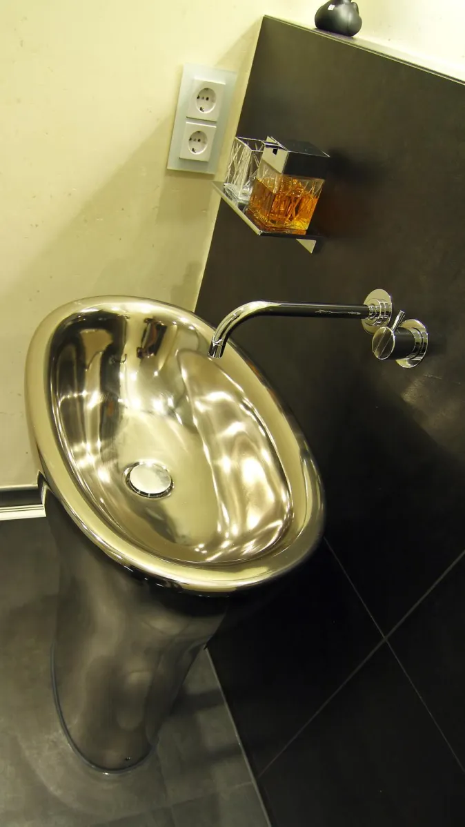 Eleganter freistehender Edelstahl-Waschtisch mit wandmontierter Armatur in einem modernen Gästebad.
