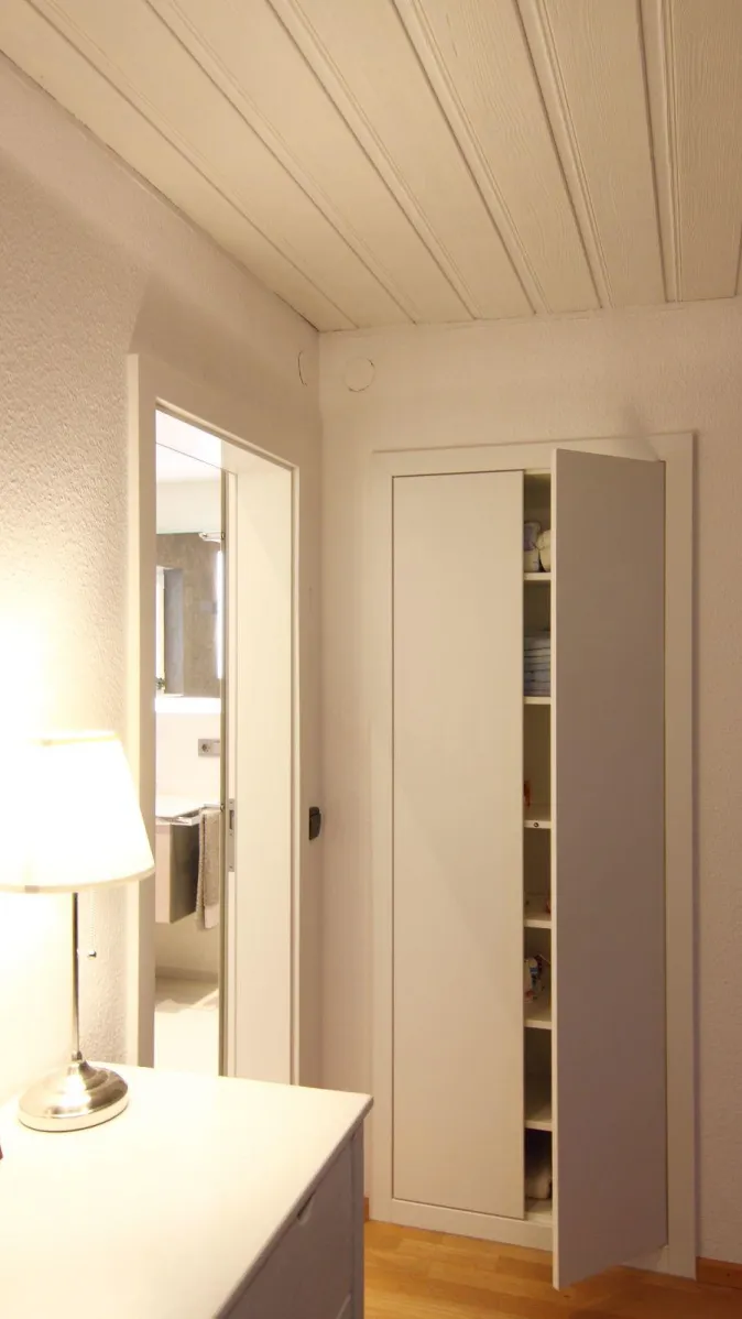 Flur mit offenem Einbauschrank und Blick ins moderne Badezimmer mit Waschtisch und Handtüchern.