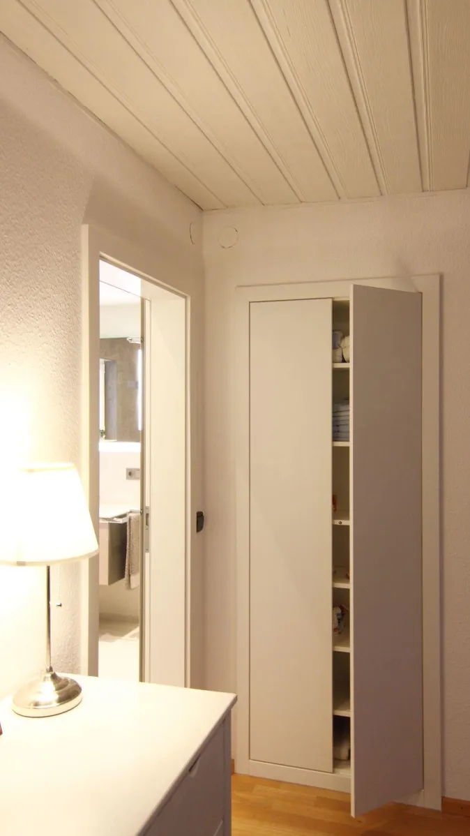 Flur mit offenem Einbauschrank und Blick ins moderne Badezimmer mit Waschtisch und Handtüchern.
