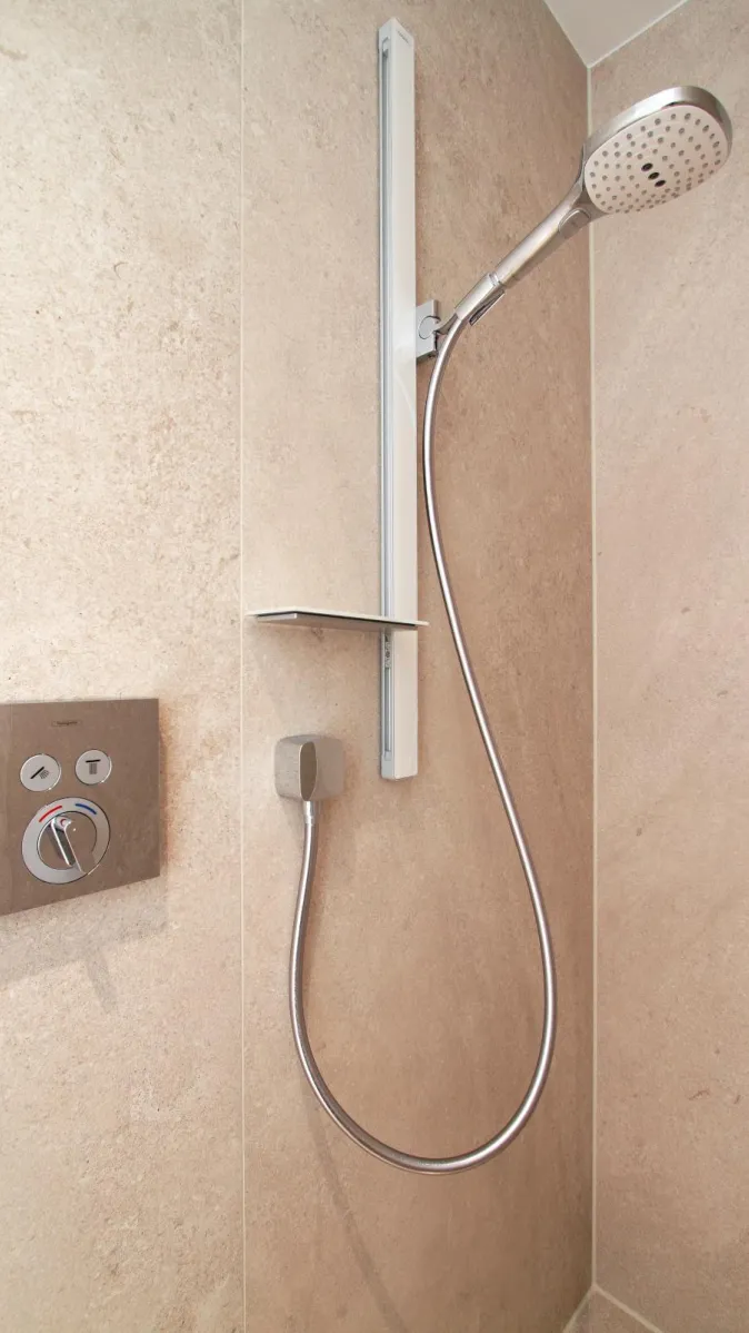 Detailansicht einer modernen Duscharmatur mit Handbrause in einer bodenebenen Dusche im Sauna-Wellnessbad.