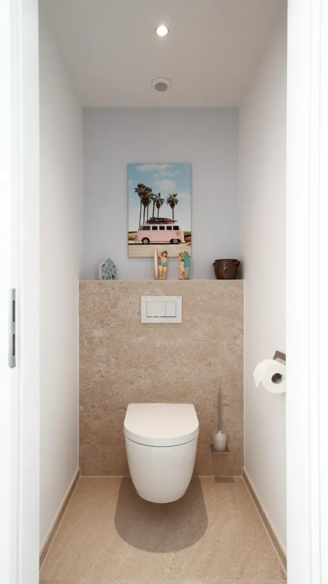 Modernes WC im Sauna-Wellnessbad mit Natursteinwand, klarer Gestaltung und dekorativen Accessoires.