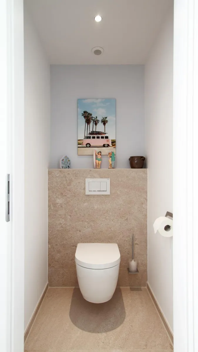 Modernes WC im Sauna-Wellnessbad mit Natursteinwand, klarer Gestaltung und dekorativen Accessoires.
