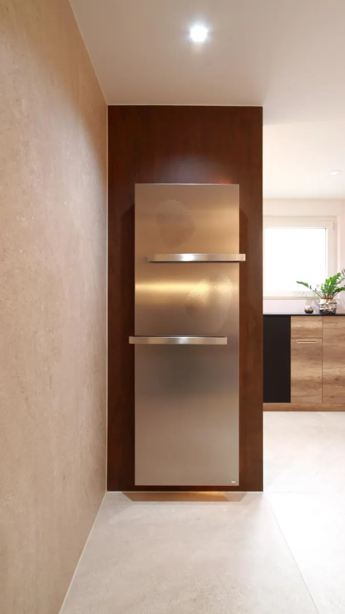 Moderner Designheizkörper mit Handtuchhaltern, stilvoll integriert in eine Holzwand im eleganten Wohnbad.