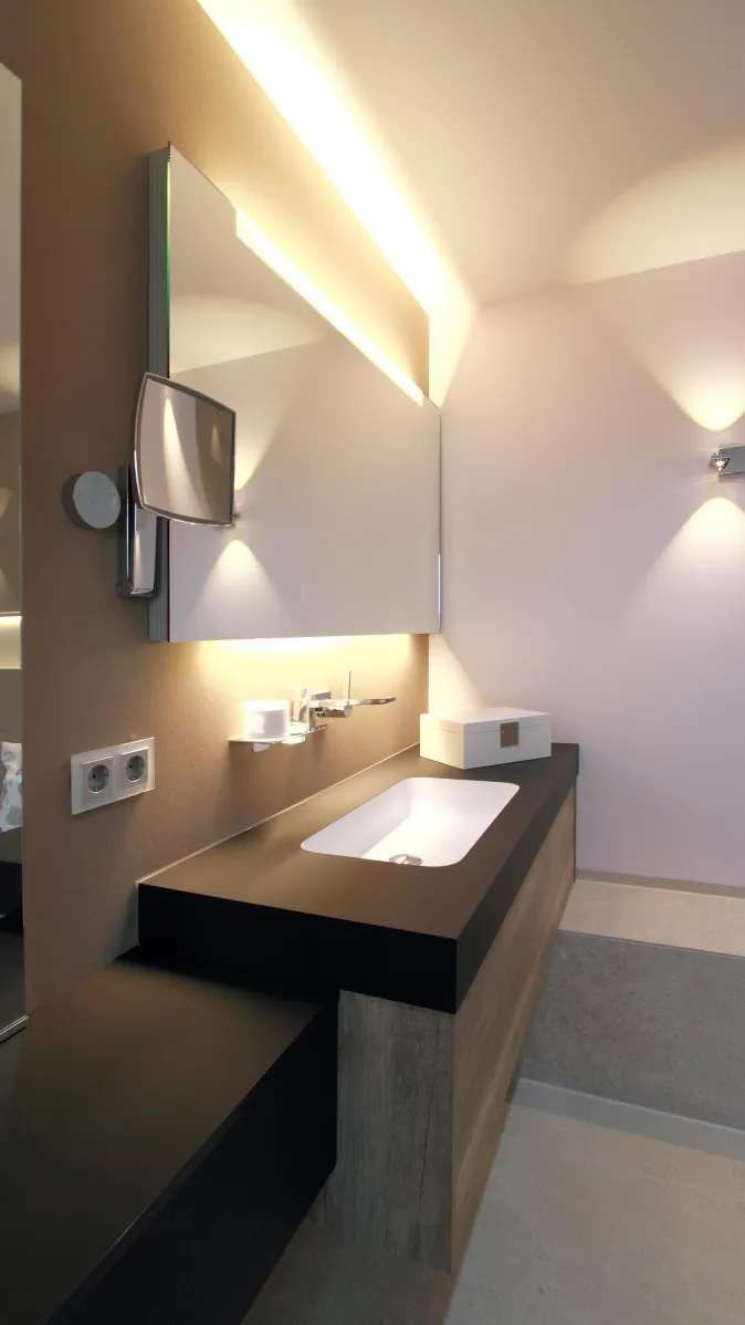 Eleganter Waschtisch mit schwarzer Fenix-Oberfläche, modernem Einbauwaschbecken und beleuchtetem Spiegel im Wohnbad.