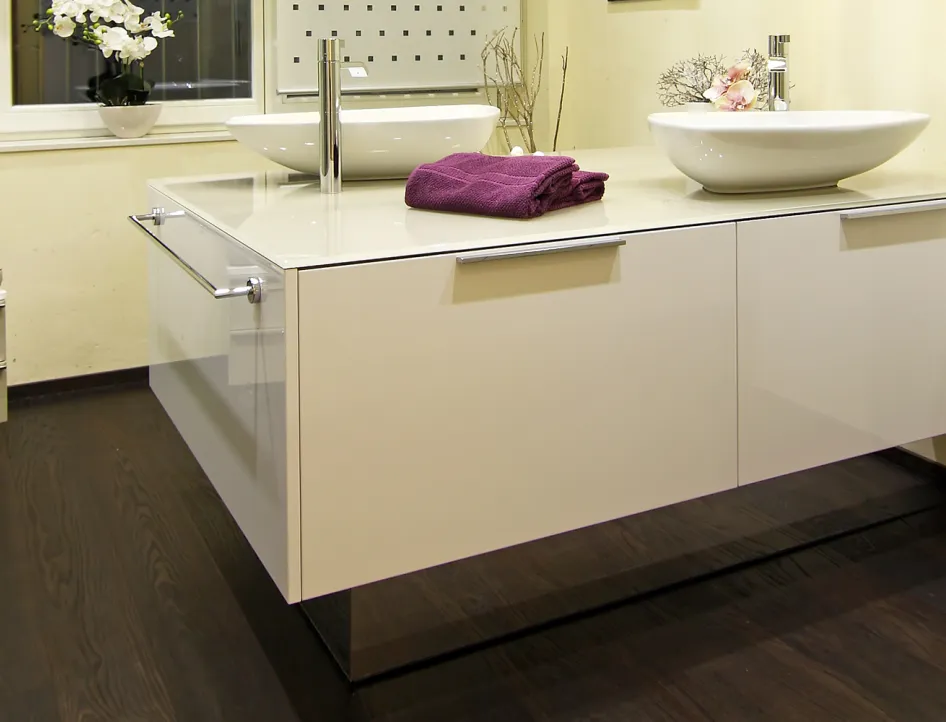 Schwebender Waschtisch mit zwei modernen Aufsatzwaschbecken, eleganter Hochglanzoberfläche, violettem Handtuch und stilvoller Dekoration im Badezimmer.