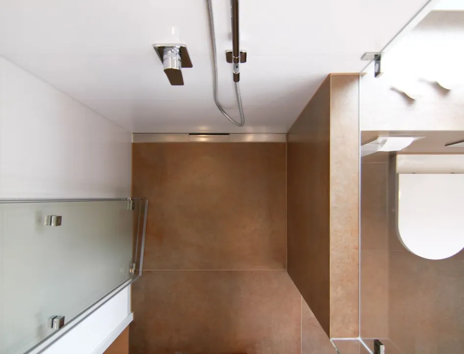 Moderne Dusche mit großer Regendusche aus der Decke, Glasabtrennung und eleganten Wandfliesen in Natursteinoptik.