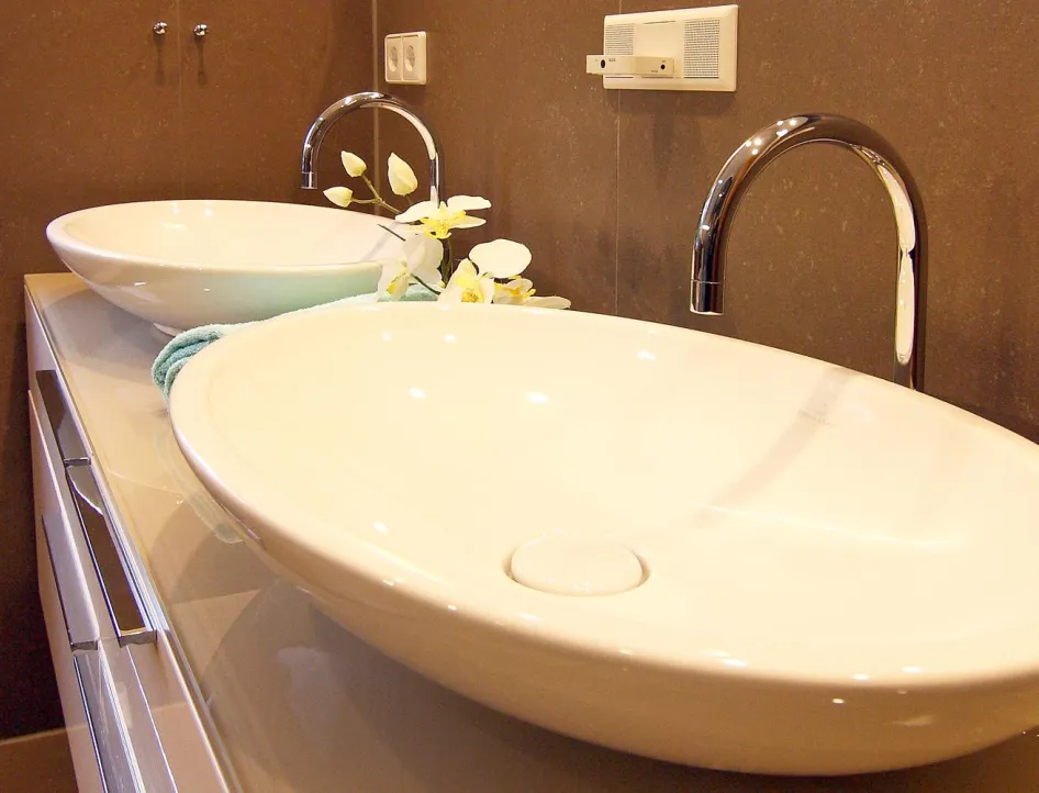 Detailaufnahme eines modernen Doppelwaschtischs mit eleganten Aufsatzwaschbecken und verchromten Armaturen im stilvollen Gästebad.
