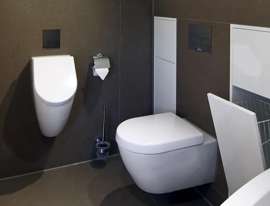 Modernes Gästebad mit wandhängendem WC und Urinal, integriertem Stauraum sowie Handtuchheizkörper in elegantem Design.
