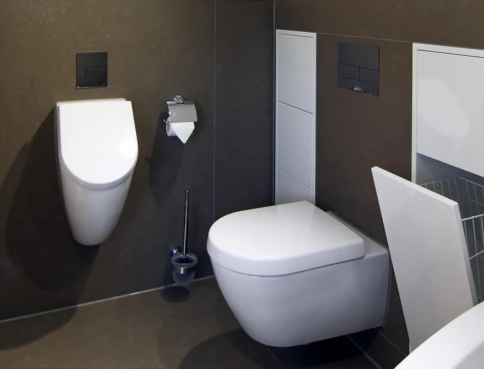 Modernes Gästebad mit wandhängendem WC und Urinal, integriertem Stauraum sowie Handtuchheizkörper in elegantem Design.