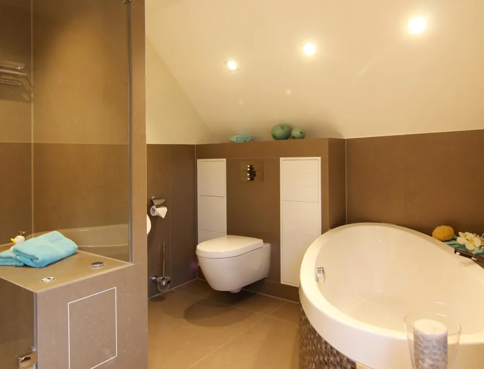 Modernes Gästebad mit Dampfdusche, WC und eleganter Badewanne, kombiniert mit warmen Braun- und Beigetönen.