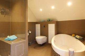 Wellnessbadezimmer mit Wanne, Dusche und WC.