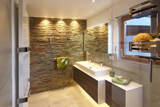 Badezimmer mit Natursteinwand, Waschtisch und Fenster.
