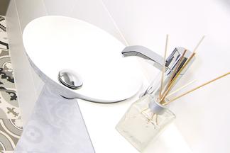 Rundes Waschbecken auf einem kleinen Waschtisch mit Wasserhahn.