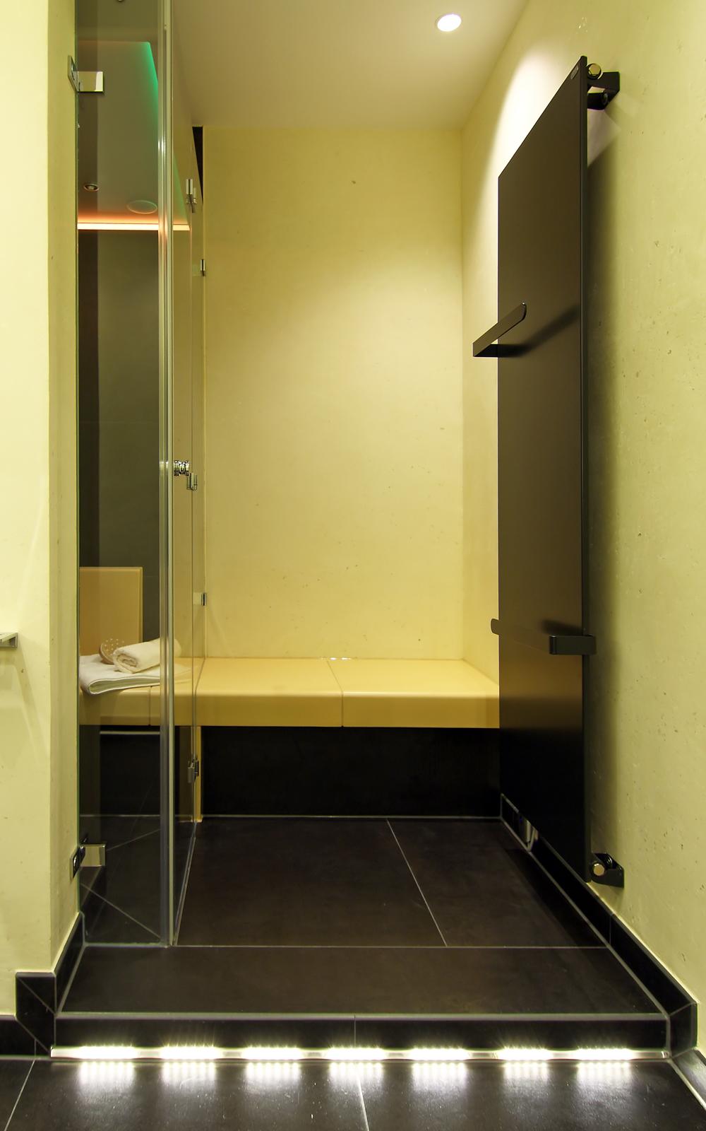 Podest mit Sitzbank und Heizkörper vor der Dusche.