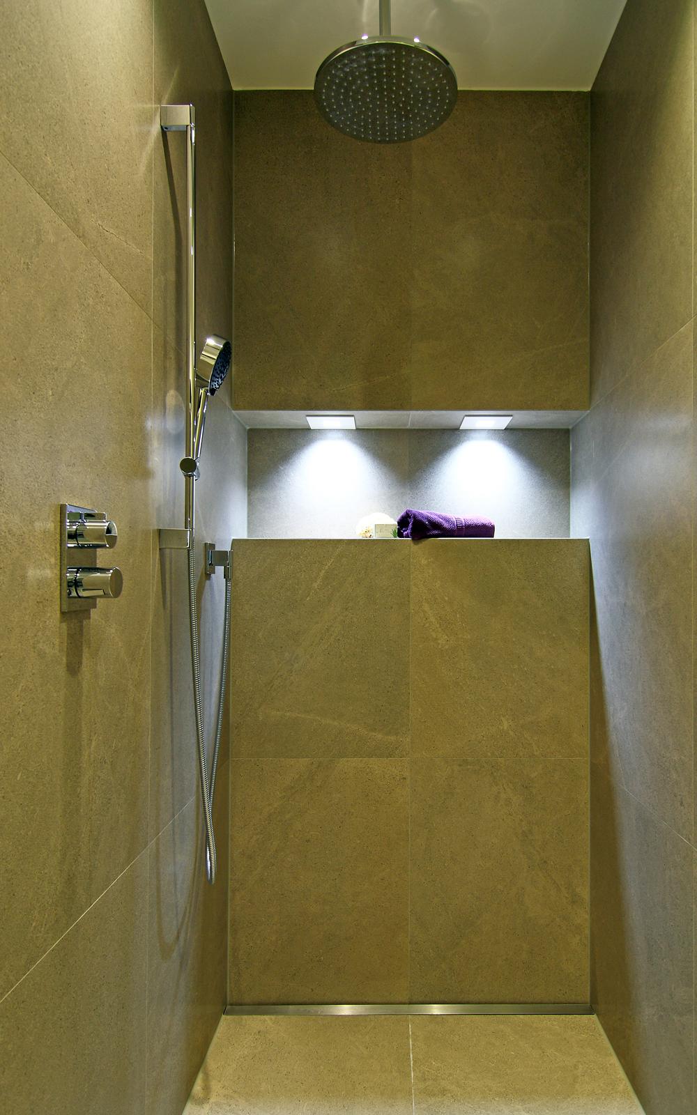 Bodenebene Dusche mit Ablagefläche, Beleuchtung und Regenduschkopf.