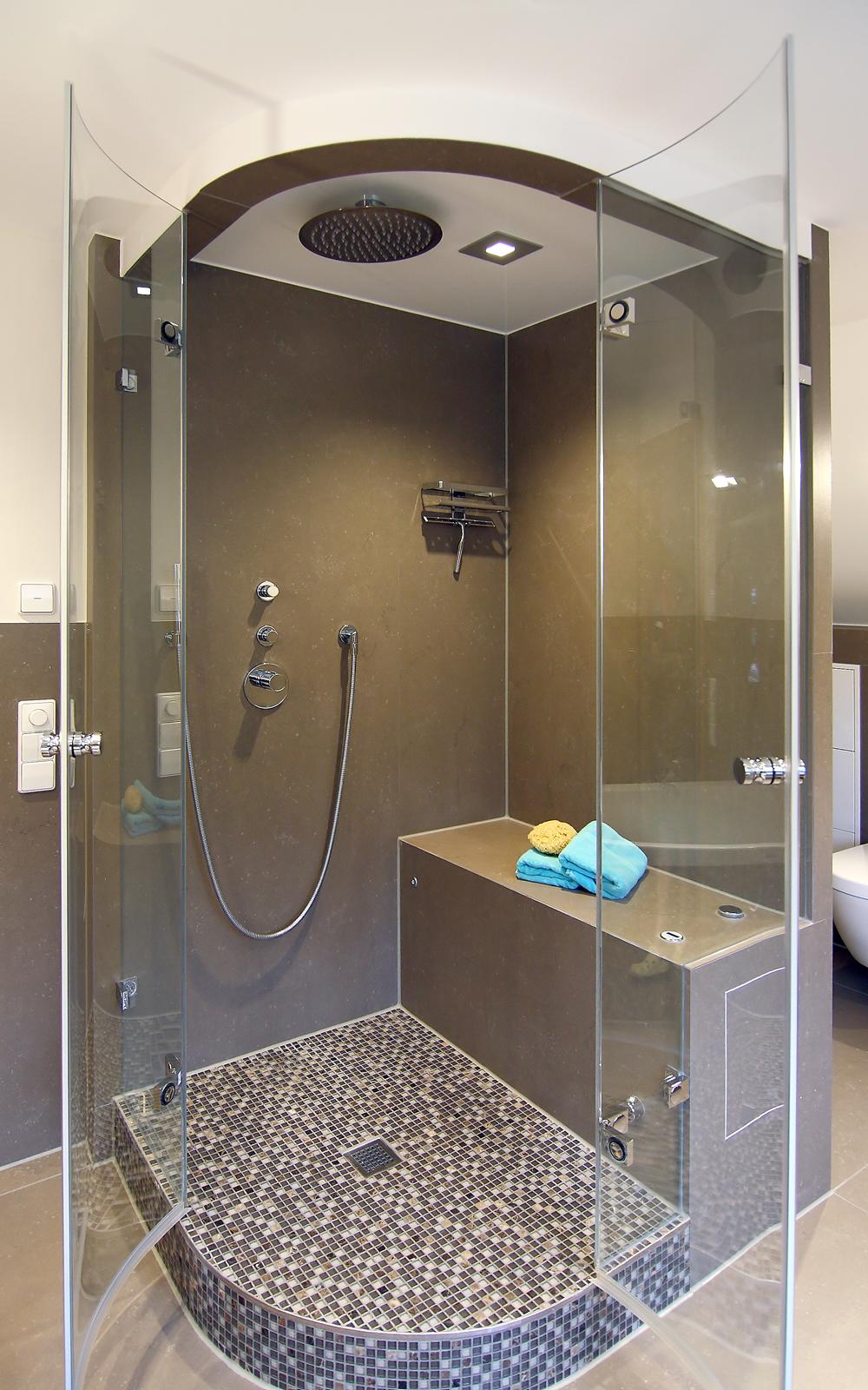 Wellnessdusche mit Sitzbank und Mosaikfliesen.