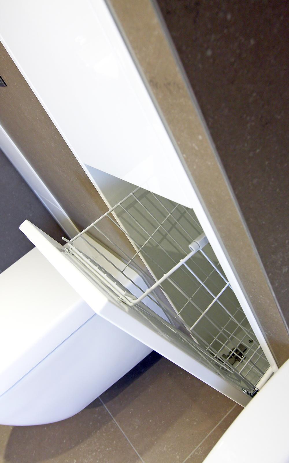Praktischer Wäsche- oder Abwurfkorb, als Fach zum ausklappen integriert in der Wand.