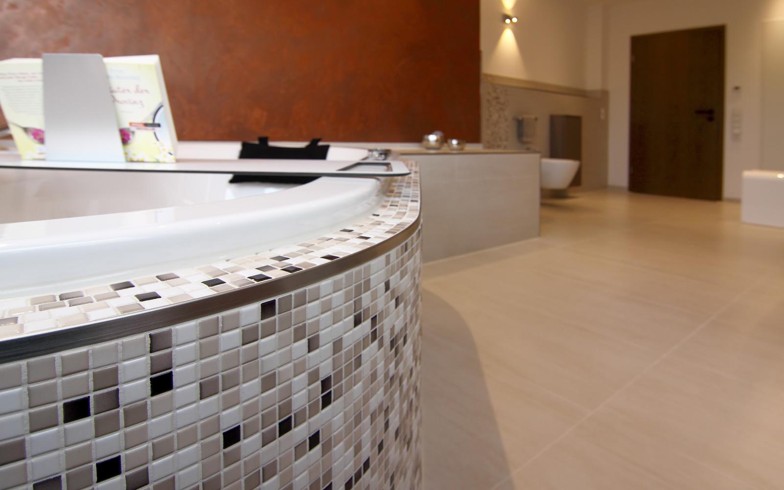 Badewanne mit Mosaikfliesen in einem geräumigen Badezimmer.