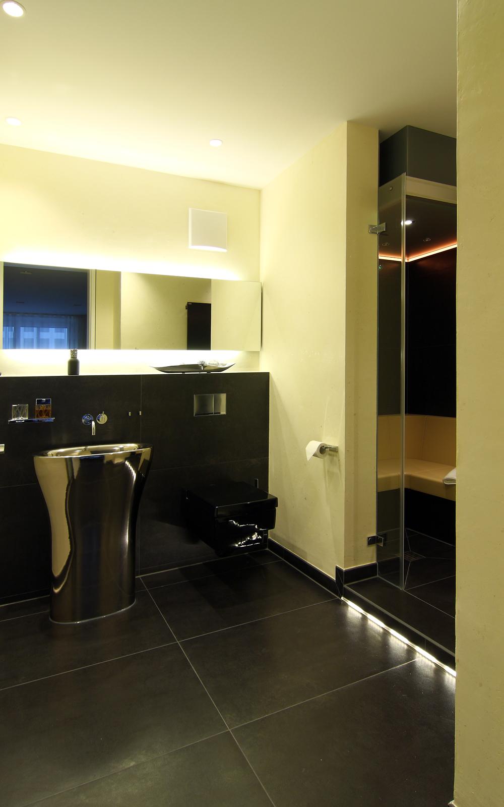 Badezimmer mit Waschtisch, großem Spiegel und Dampfdusche.